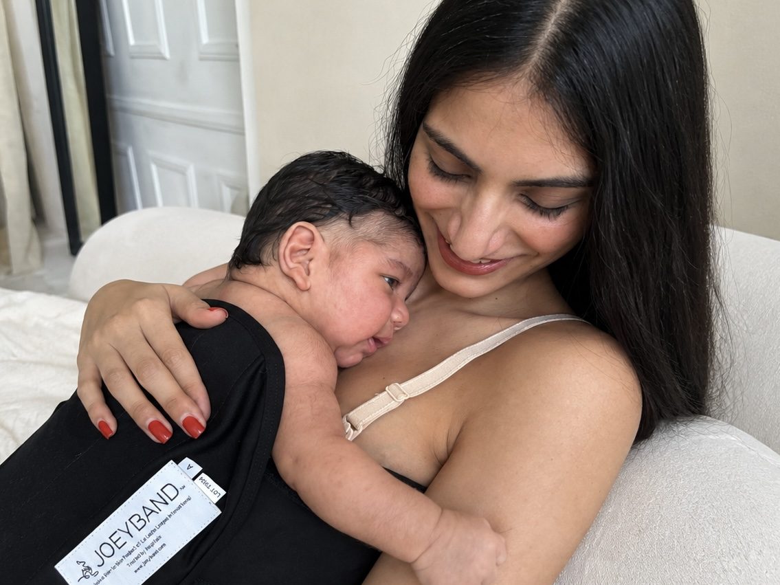 Parent holding a baby secured skin-to-skin in a Joeyband